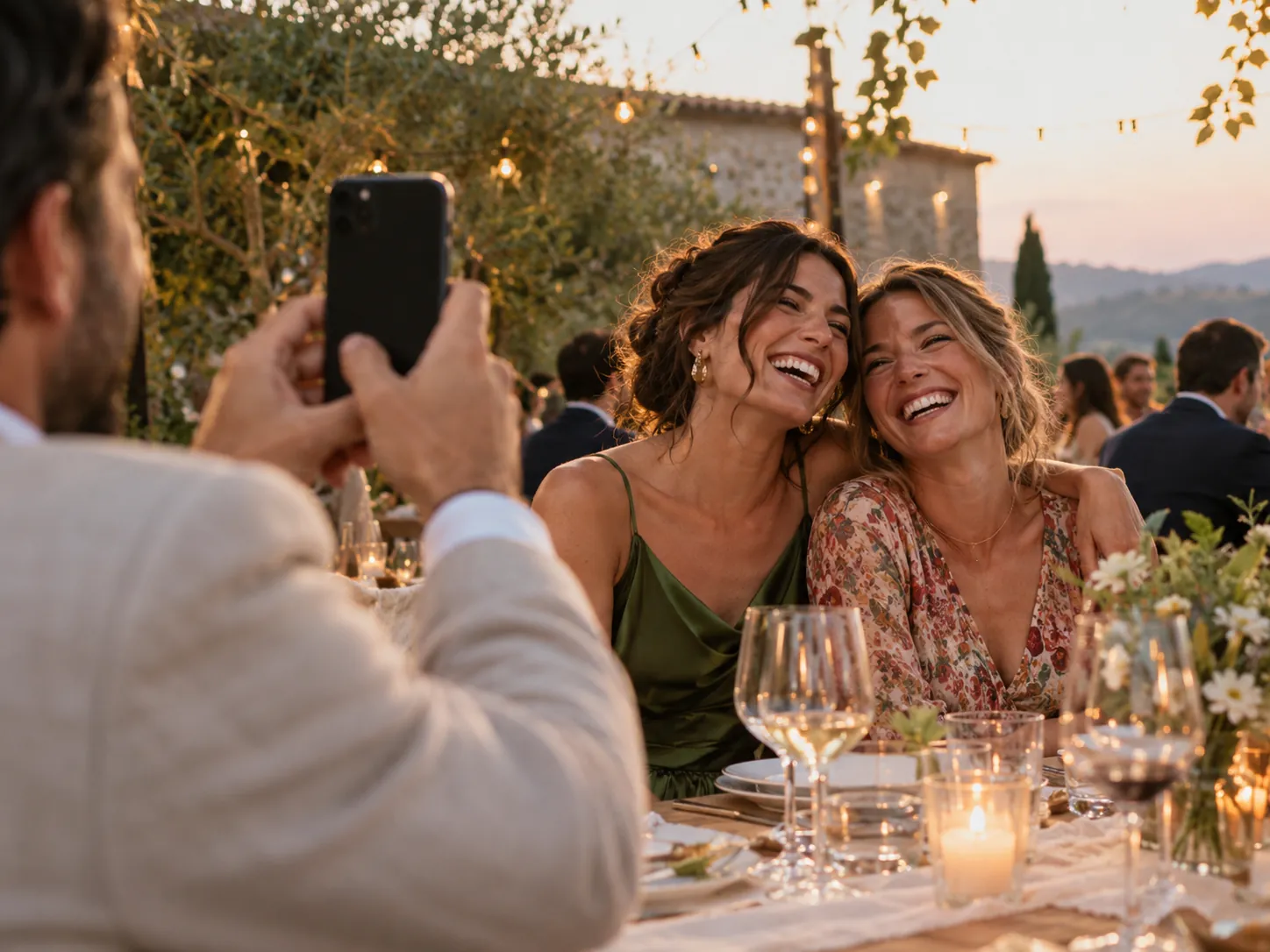 Un invitado fotografía con su celular a dos amigas en una celebración